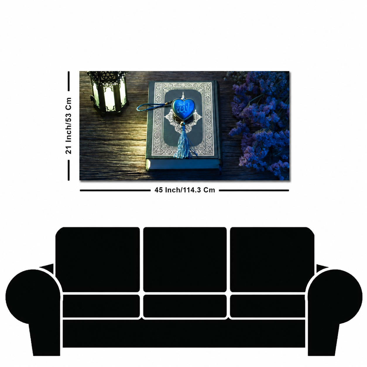 A rectangular wall art print or canvas showing a decorative blue book with a tassel bookmark on a dark wooden surface, labeled with dimensions 21 inch by 45 inch. Below the artwork is a large black sofa silhouette on a white background.
